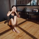 Girl in the room closes her eyes from the sun while sitting on the floor