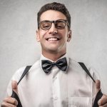 A man in a white shirt, bow tie, suspenders, glasses