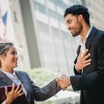 A man in a business suit smiles while holding the hand of a girl in a jacket