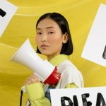 Inscriptions in English and a girl with a loudspeaker on a yellow background